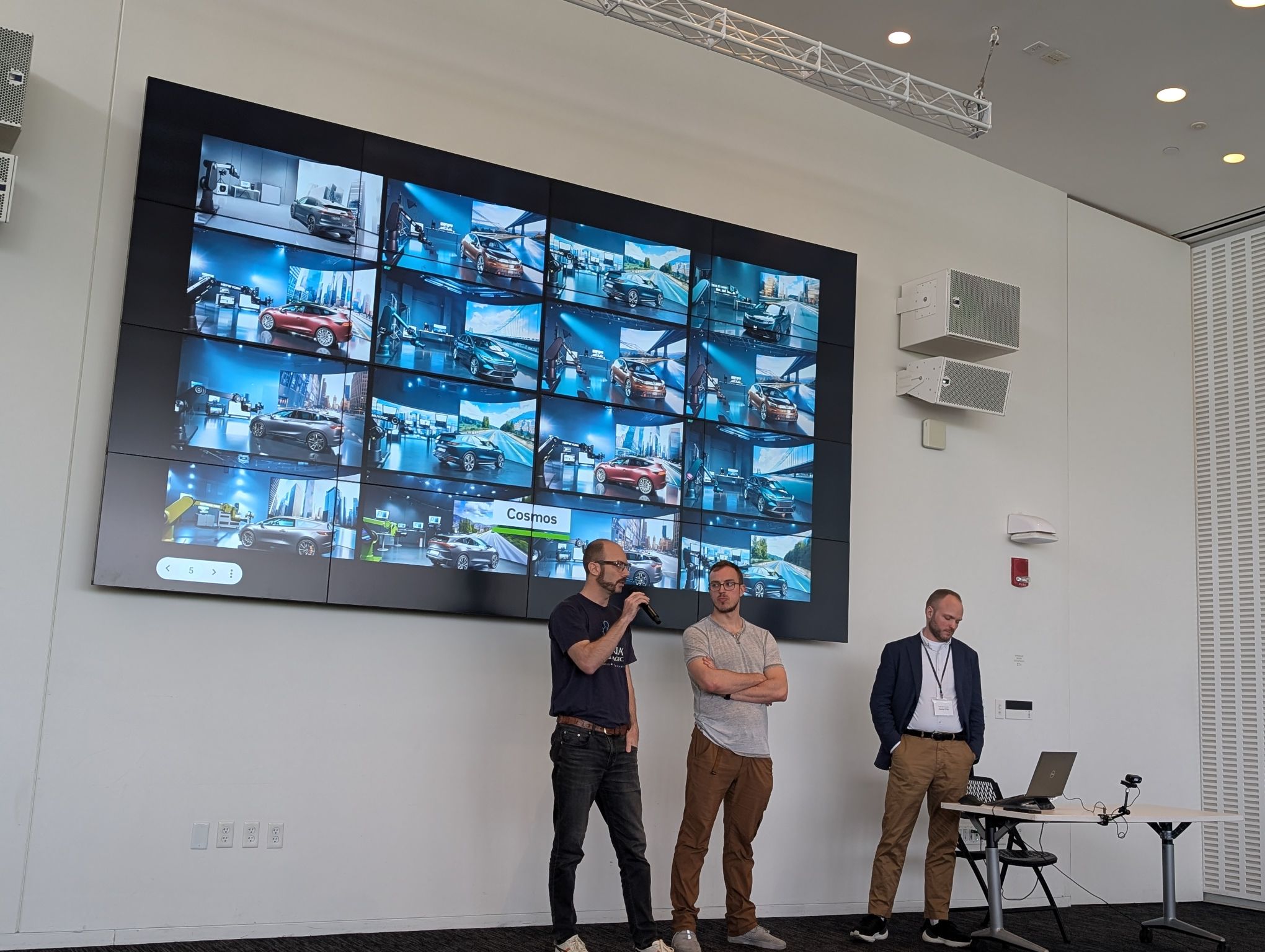 Martin presenting alongside two colleagues in front of a large video wall showing a grid of AI-generated car renders under an NVIDIA Cosmos label